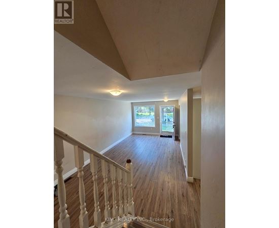 A hallway with wood floors and white railings leading to a door.