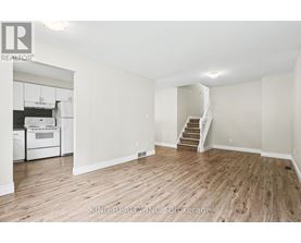 A spacious room with wooden flooring and a staircase leading to another room.