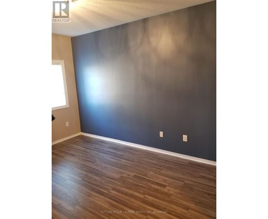 A room with wooden flooring and a dark wall.