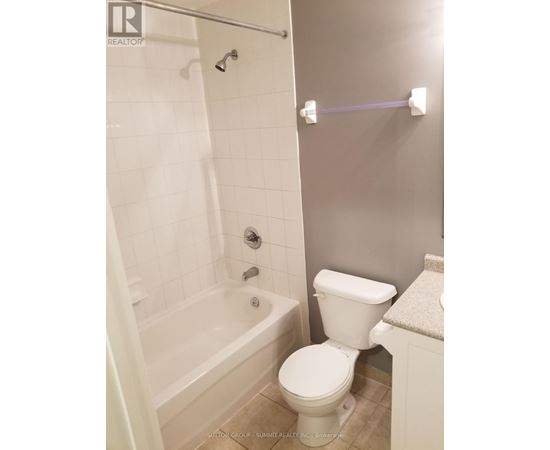 A white toilet in a bathroom with a white tiled shower.