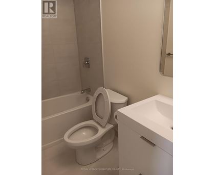 A white toilet in a bathroom with a sink and mirror.