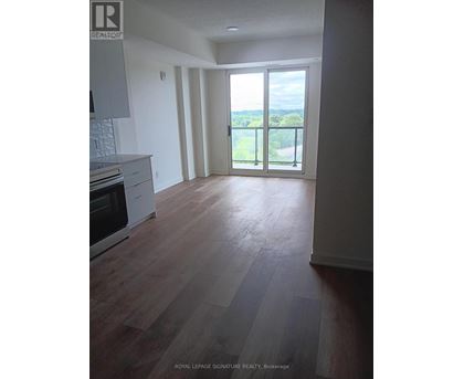 A spacious room with wooden flooring and a view of the outdoors through a sliding glass door.