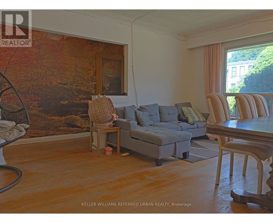 A living room with a grey couch and a large painting on the wall.