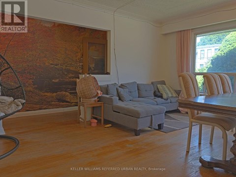 A living room with a grey couch and a large painting on the wall.