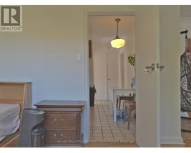 A bedroom with a bed, dresser and a small table with chairs in a hallway.