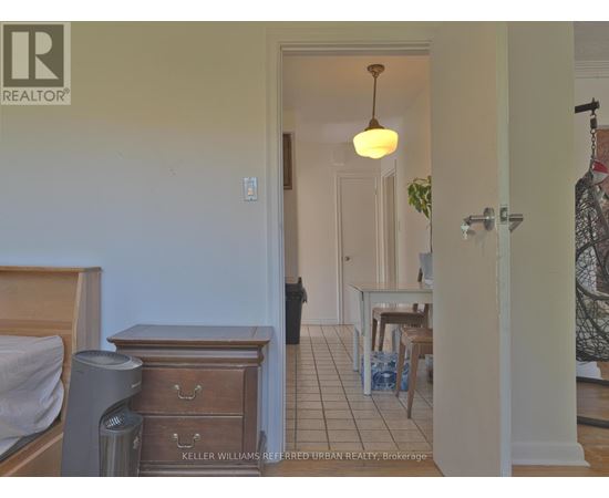 A bedroom with a bed, dresser and a small table with chairs in a hallway.