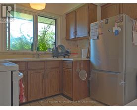 A kitchen with wooden cabinets and a refrigerator with magnets and notes on it.