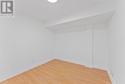 A white room with wooden flooring and a ceiling light.