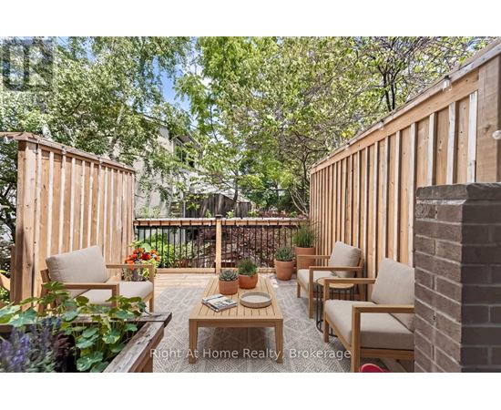 A wooden deck with chairs and a table surrounded by greenery.