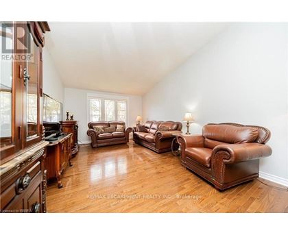 A living room with brown leather furniture and wooden floors.
