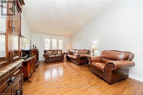 A living room with brown leather furniture and wooden floors.