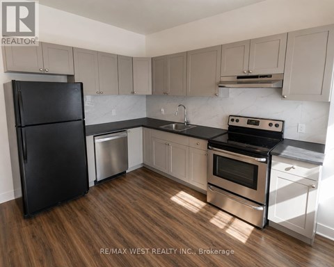 A kitchen with a black fridge, stainless steel oven and white cabinets.