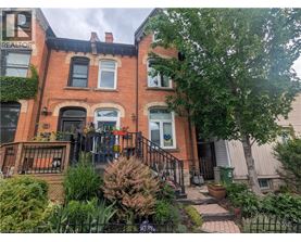 A red brick house with a black iron fence and a green trash can.