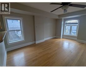 A room with a ceiling fan and two windows.