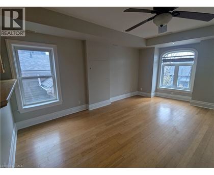 A room with a ceiling fan and two windows.