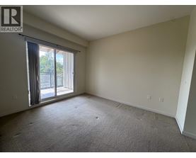 A spacious room with a sliding glass door leading to a balcony.