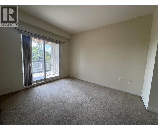 A spacious room with a sliding glass door leading to a balcony.