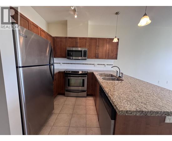 A kitchen with a refrigerator, microwave, oven, and sink.