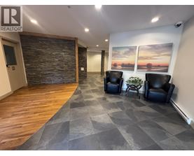 A living room with a stone wall and two black leather chairs.