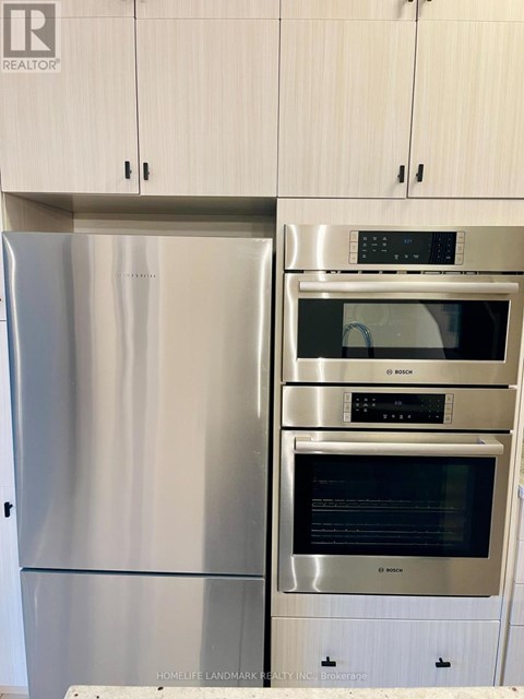 A stainless steel refrigerator and oven in a kitchen.