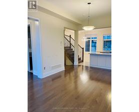 A spacious room with wooden floors and a staircase.