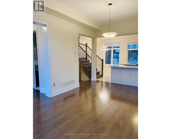 A spacious room with wooden floors and a staircase.