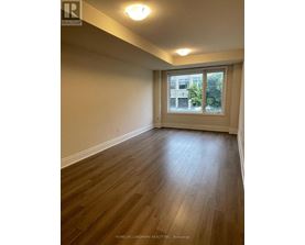 A room with wooden flooring and a window showing a building outside.
