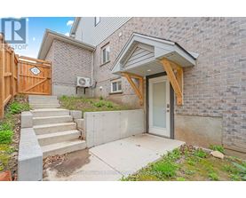 A house with a wooden fence and a concrete staircase leading to a glass door.