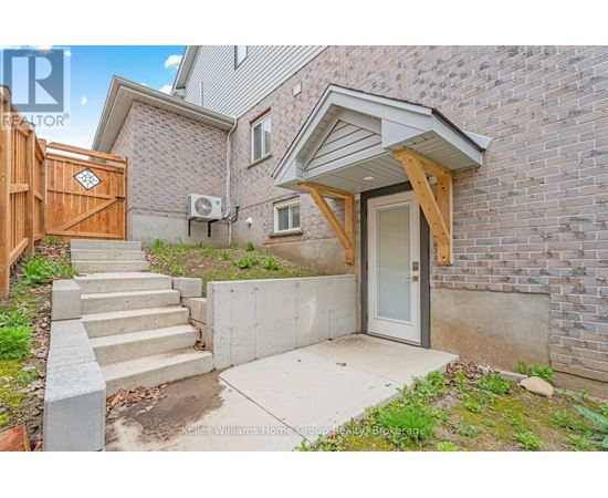 A house with a wooden fence and a concrete staircase leading to a glass door.