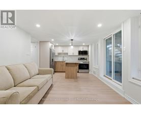 A well-lit, modern kitchen and living room with a beige sofa.
