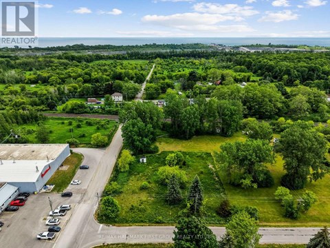 A bird's eye view of a green landscape with a building and cars.