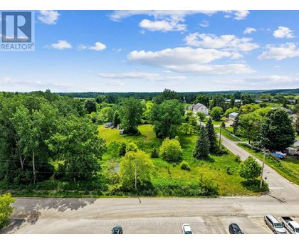 A bird's eye view of a residential area with houses, trees, and a parking lot.