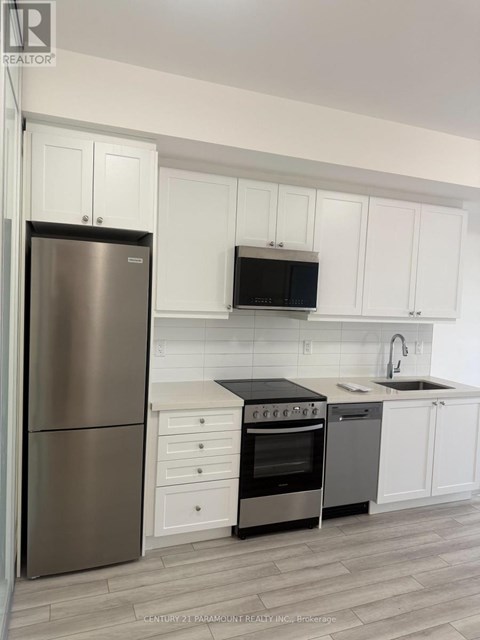 A kitchen with white cabinets and a stainless steel refrigerator.