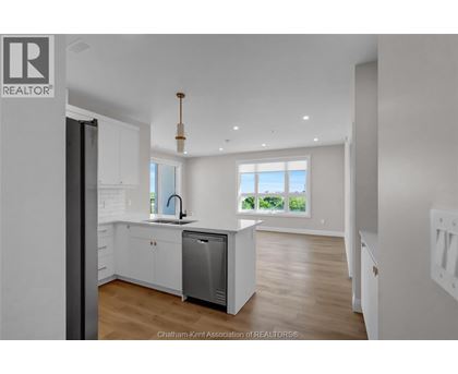 A modern kitchen with white cabinets and a large window.