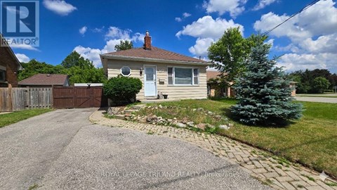 A house with a driveway and a tree in front of it.