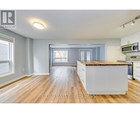 A well-lit kitchen with wooden floors and white cabinets.