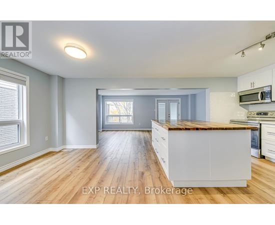 A well-lit kitchen with wooden floors and white cabinets.