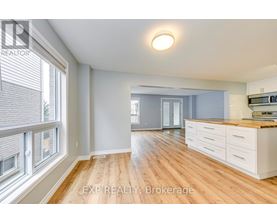 A well-lit, spacious kitchen with wooden floors and white cabinetry.