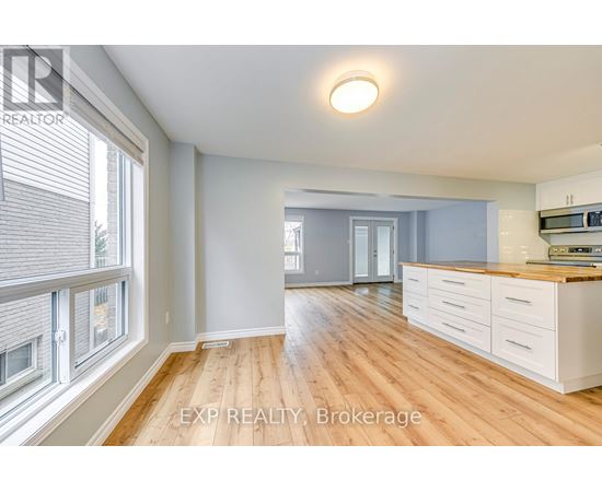 A well-lit, spacious kitchen with wooden floors and white cabinetry.