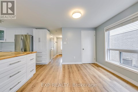 A kitchen with white cabinets and a wooden floor.
