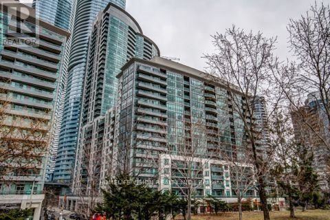A modern building with glass windows and balconies is surrounded by bare trees.