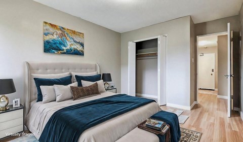 A bedroom with a large bed and a painting on the wall.