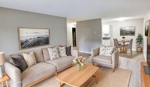 A living room with a grey couch, a wooden coffee table, and a painting on the wall.