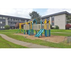 A playground with a blue slide and yellow climbing frame.