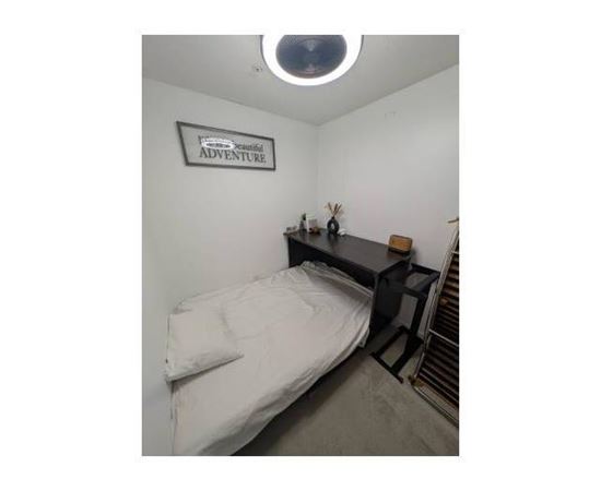 A small bedroom with a bed, a desk, and a sign on the wall that says "Adventure".