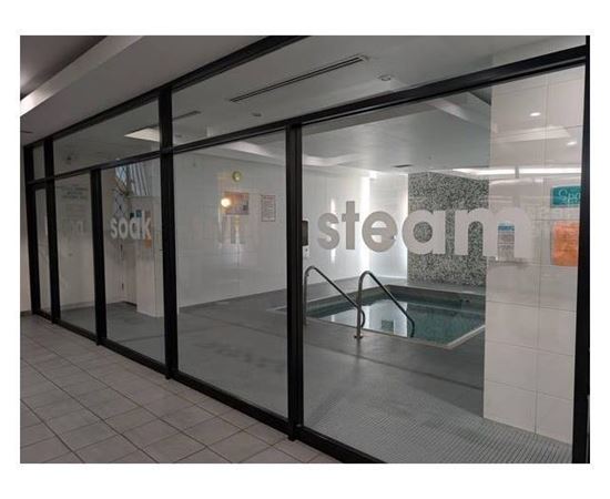 A glass door with a pool in the background and the word steam on the wall.