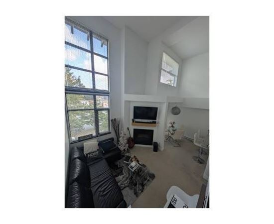 A living room with a black couch and a television.