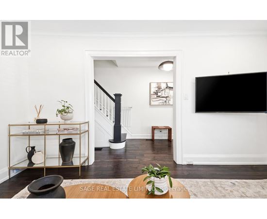 A living room with a black sofa and a TV on the wall.