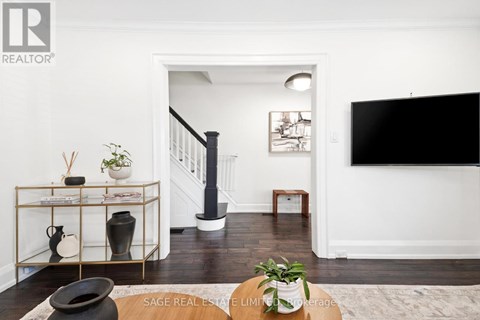A living room with a black sofa and a TV on the wall.
