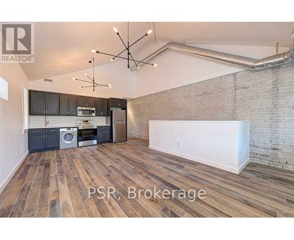 A room with wooden floors and a brick wall is for sale.